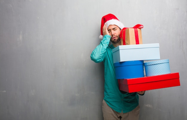 Foto giovane che porta un cappello della santa che tiene i regali stanchi e molto assonnati