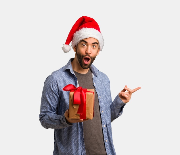 Young man wearing santa hat holding something with hand