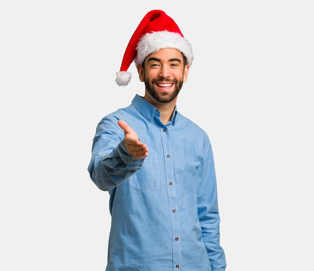 Young man wearing santa hat reaching out to greet someone