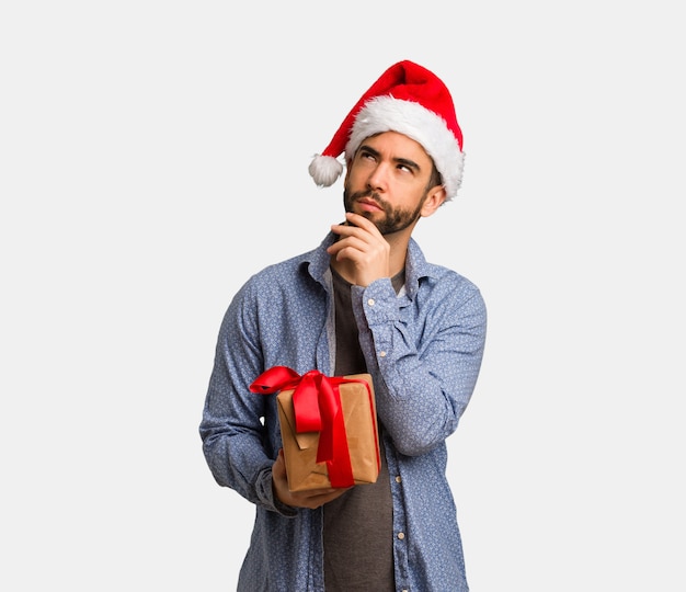 Молодой человек в шляпе Санта, думая о идее
