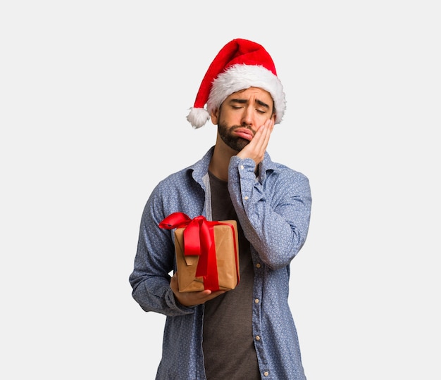 Young man wearing santa hat tired and very sleepy