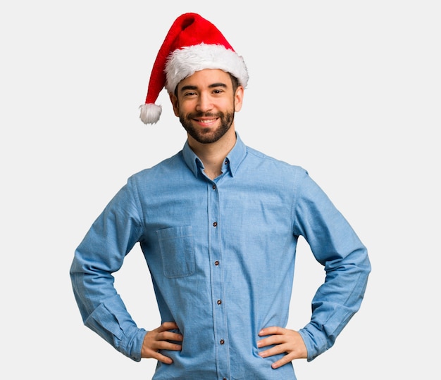 Young man wearing santa hat with hands on hips