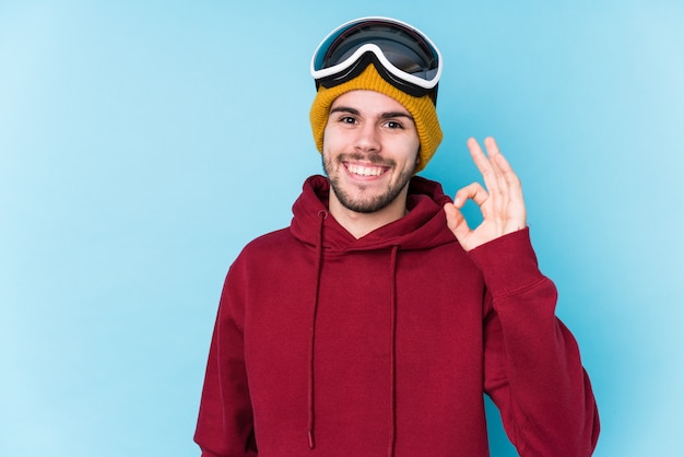 Young man wearing a ski clothes isolated cheerful and confident showing ok gesture