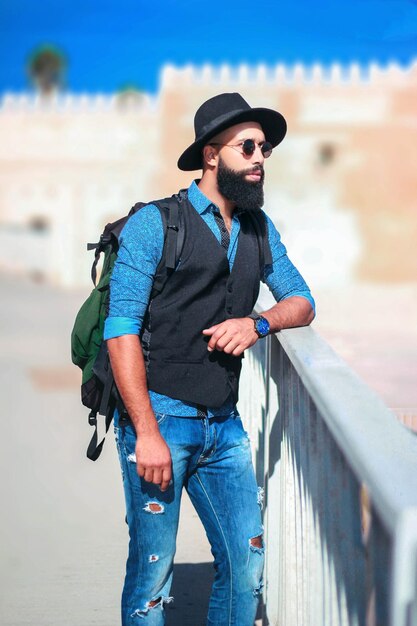 Young man wearing sunglasses while standing in city during sunny day