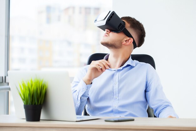 Молодой человек в очках виртуальной реальности в современном офисе.