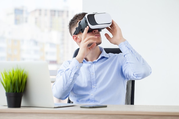 Young man wearing virtual reality goggles in modern coworking studio.