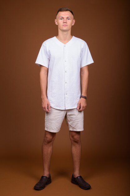 茶色の背景に白いシャツを着ている若い男