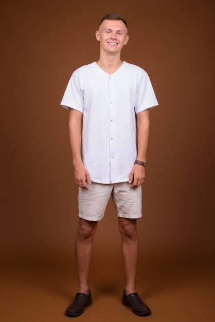 Young man wearing white shirt against brown background