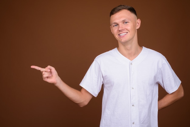 Young man wearing white shirt against brown background