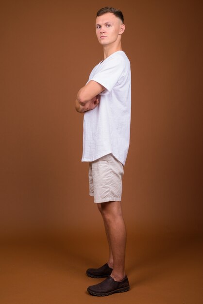 Young man wearing white shirt against brown background