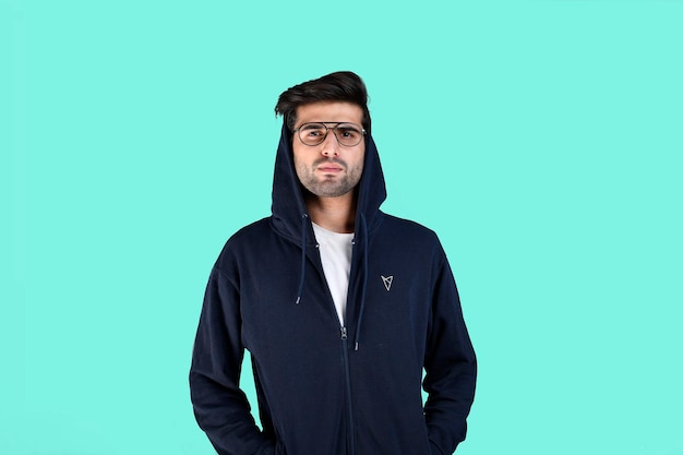 young man wearing winter clothes and glasses on blue background indian pakistani model