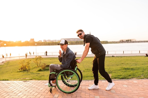 Young man in wheelchair and his friend walk outdoors high quality photo