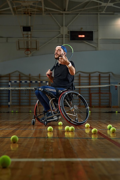 Photo young man in wheelchair playing tennis on court