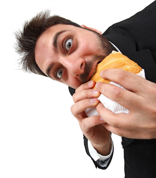 Молодой человек быстро ест бутерброд
