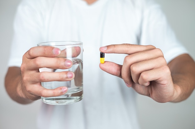 A young man in a white dress is about to eat a pill.