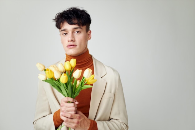 変更されていない黄色い花のエレガントなスタイルの背景の花束と白いジャケットの若い男