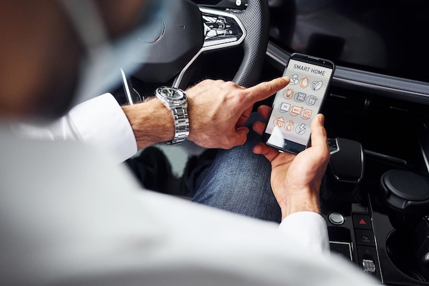 Young man in white shirt is sitting inside of a modern new automobile