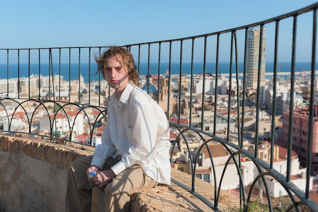 Young man in a white shirt looking at the camera with the city of Alicante in the background