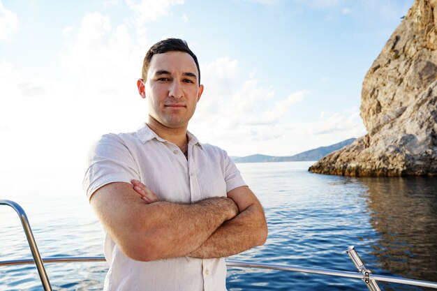 Young man in white shirt standing on the nose yacht in the open sea