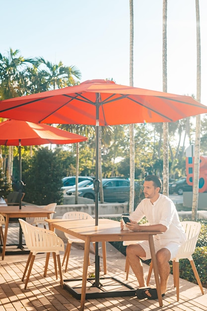 Young man in white shirt working on laptop in outdoor cafe