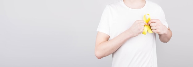 自殺の黄色いリボンの意識のシンボルを保持している白いTシャツの若い男