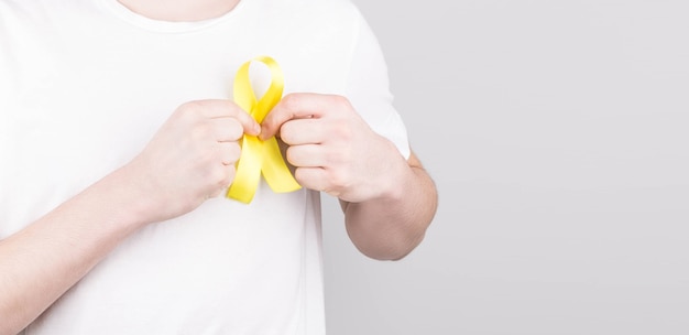 Young man in white t-shirt holding yellow ribbon awareness symbol for suicide