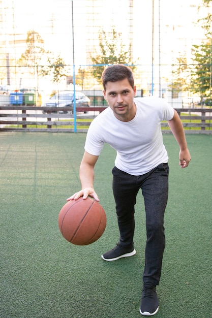 Foto giovane uomo in una maglietta bianca che gioca a basket
