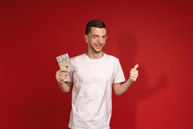 A young man in a white Tshirt with Treacher Syndrome is holding a passport