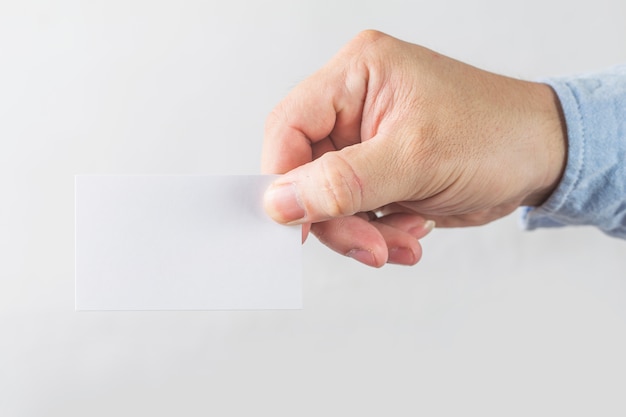 Young man who takes out blank business card from the pocket of his shirt