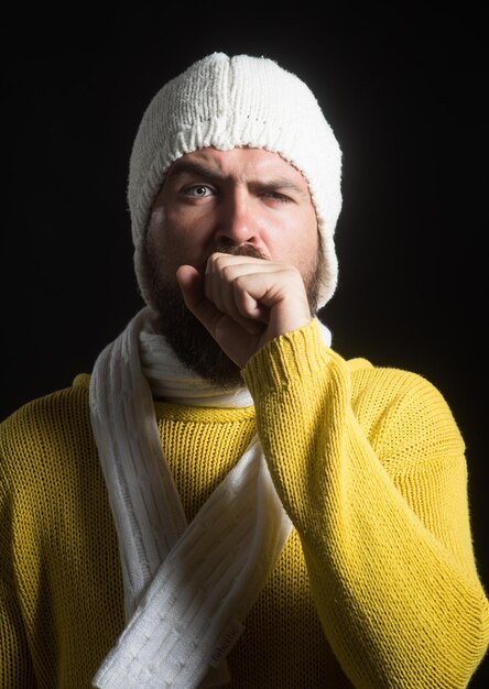 Young man wiht long beard sick, coughing, with hand in front of his mouth. Cold. Cough. Attractive guy and health problems. Medication, healthcare concept.