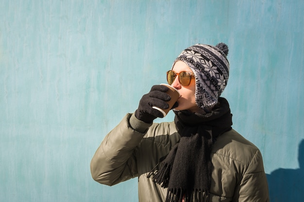 Photo young man in winter clothes holds cup of coffee