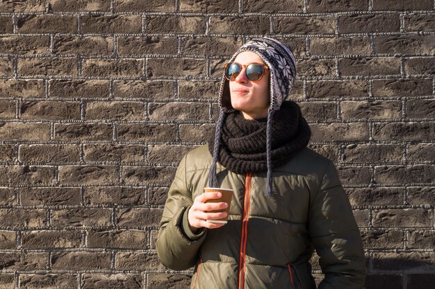 Young man in winter clothes holds cup of coffee