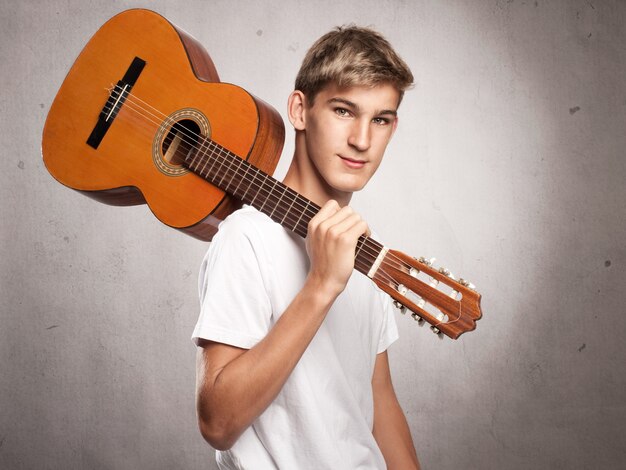 Young man with acoustic guitar on gray