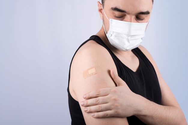 Young man with adhesive bandage on his arm after corona vaccination.