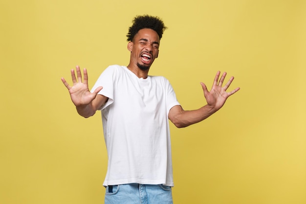 Photo young man with arms raised standing against yellow background