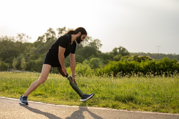 Foto giovane con gamba artificiale che ha attività di fitness in un parco pubblico caldo sole