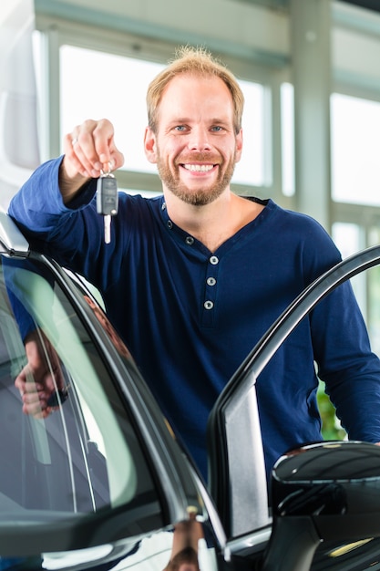 Foto giovane con auto nel concessionario auto