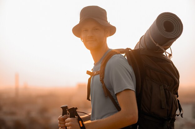 A young man with backpack going hiking and carrying his backpack and a mat