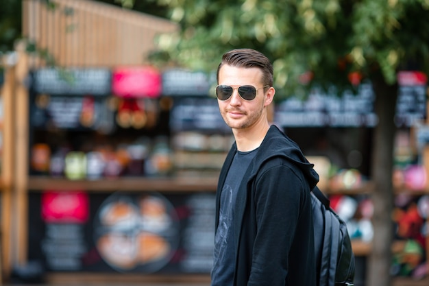 Young man with backpack on street food market outdoors