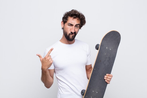 Young man with a bad attitude looking proud and aggressive, pointing upwards or making fun sign with hands