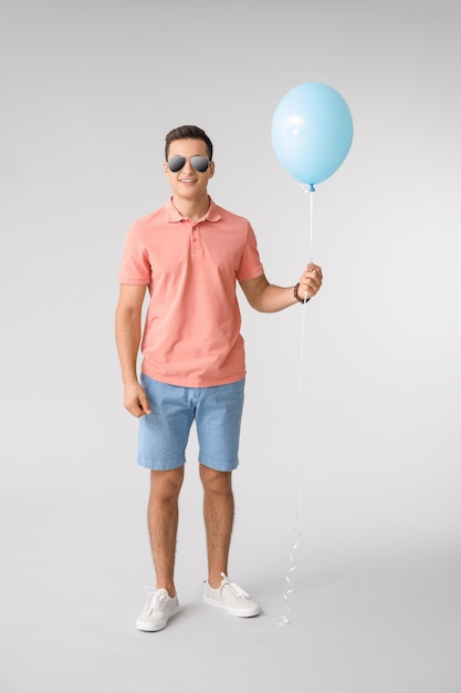 Young man with balloon on grey