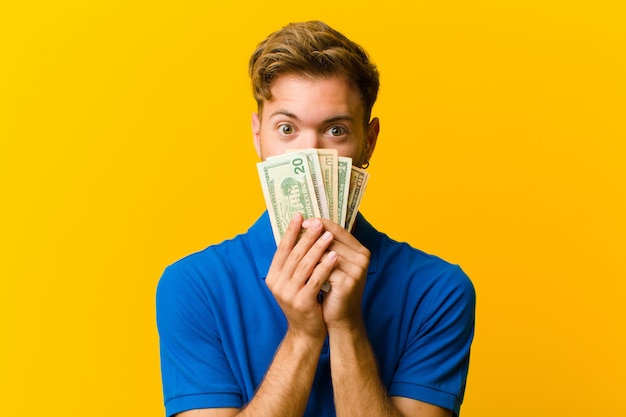 Young man with banknotes against orange