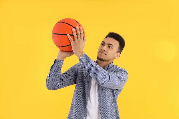 노란색 배경에 농구 공을 든 젊은 남자