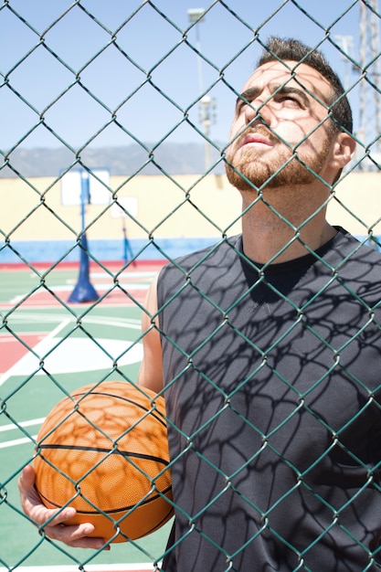 young man with the basketball behind a fence