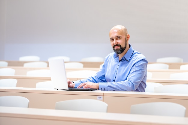 young man with beard in classroom with white laptop