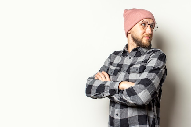 young man with a beard in a hat, plaid shirt and glasses looks back on an isolated white.