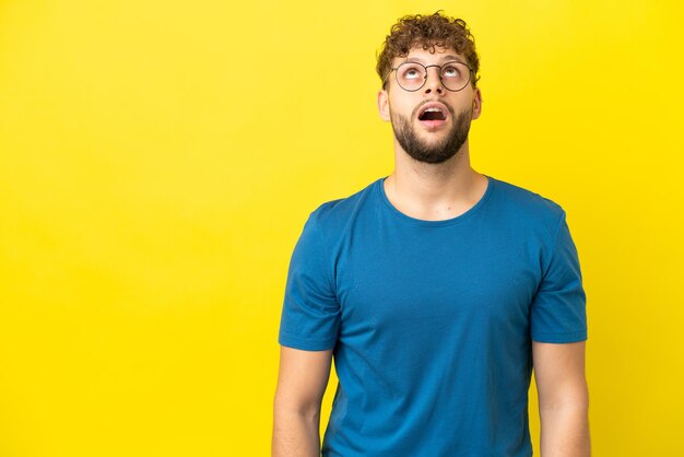 Young man with beard over isolated blue background with surprise facial expression