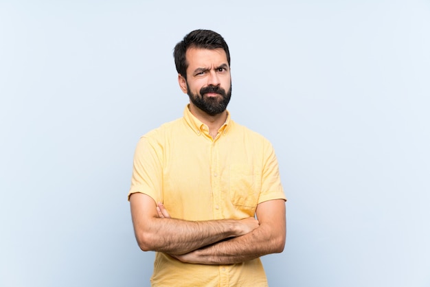 Photo young man with beard over isolated blue   feeling upset