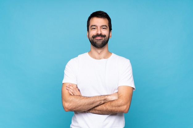 Foto giovane con la barba sul blu isolato mantenendo le braccia incrociate in posizione frontale