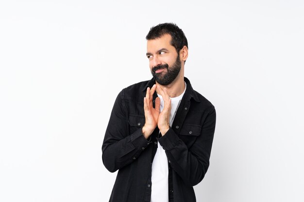 Young man with beard over isolated white scheming something